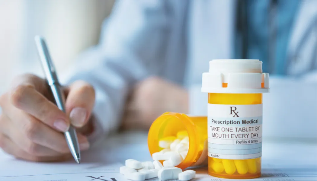 Médecin qui rédige une ordonnance à côté d'un flacon de médicaments